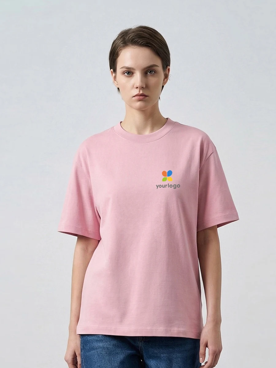 Woman wears a pink breathable, moisture-wicking base layer top with a minimalist rainbow logo on the chest, paired with blue jeans and a black T-shirt. The image reflects a minimalist commuting style, ideal for outdoor activities, combining comfort, functionality, and subtle branding in a clean, figurative design.